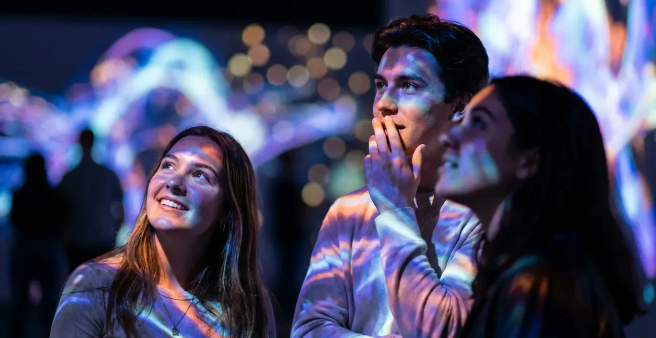 Groupe de jeunes visiteurs photographiés dans une exposition immersive avec projections monumentales